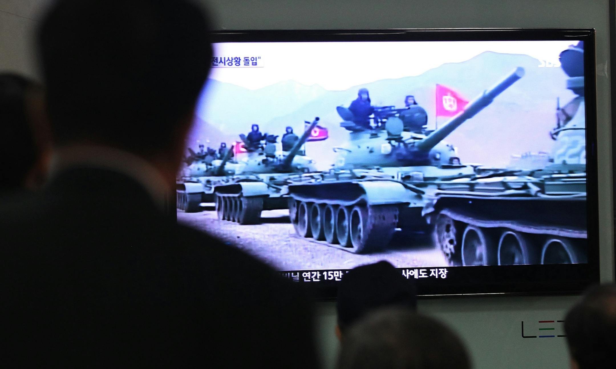 People in Seoul, South Korea, watch a news report showing North Korean army tanks.
