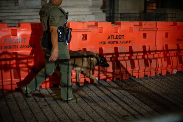 A deputy walks a barricade erected before dawn outside the Fulton County Courthouse in Atlanta, on Aug. 15, 2023.