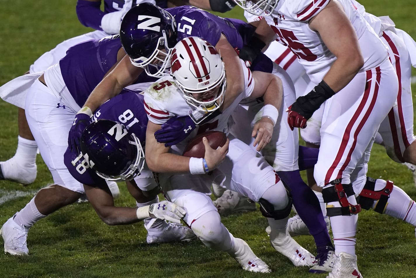 Wisconsin quarterback Graham Mertz (5) is sacked by Northwestern cornerback Cam Ruiz, left, and linebacker Blake Gallagher during the second half of an NCAA college football game in Evanston, Ill., Saturday, Nov. 21, 2020. Northwestern won 17-7. (AP Photo/Nam Y. Huh)