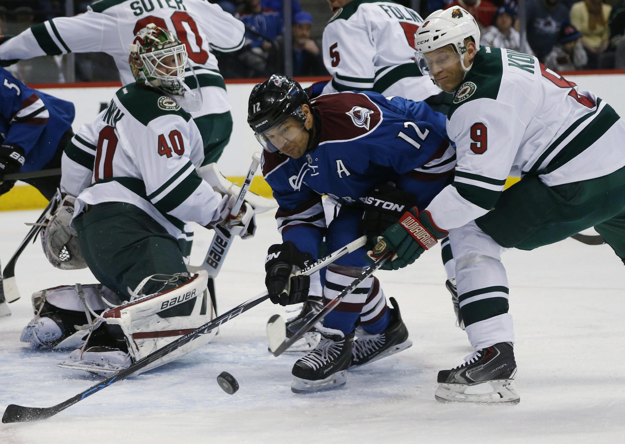 Colorado Avalanche right wing Jarome Iginla, center, fights for control of the puck as Minnesota Wild goalie Devan Dubnyk, left, and center Mikko Koivu, of Finalnd, defend in the first period of an NHL hockey game Saturday, Feb. 28, 2015, in Denver. (AP Photo/David Zalubowski)