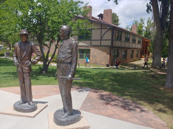 Statues of J. Robert Oppenheimer, left, and Gen. Leslie Groves stand outside the historic Fuller Lodge in Los Alamos, N.M.