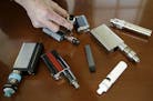 FILE - In this April 10, 2018, file photo, a high school principal displays vaping devices that were confiscated from students in such places as restr