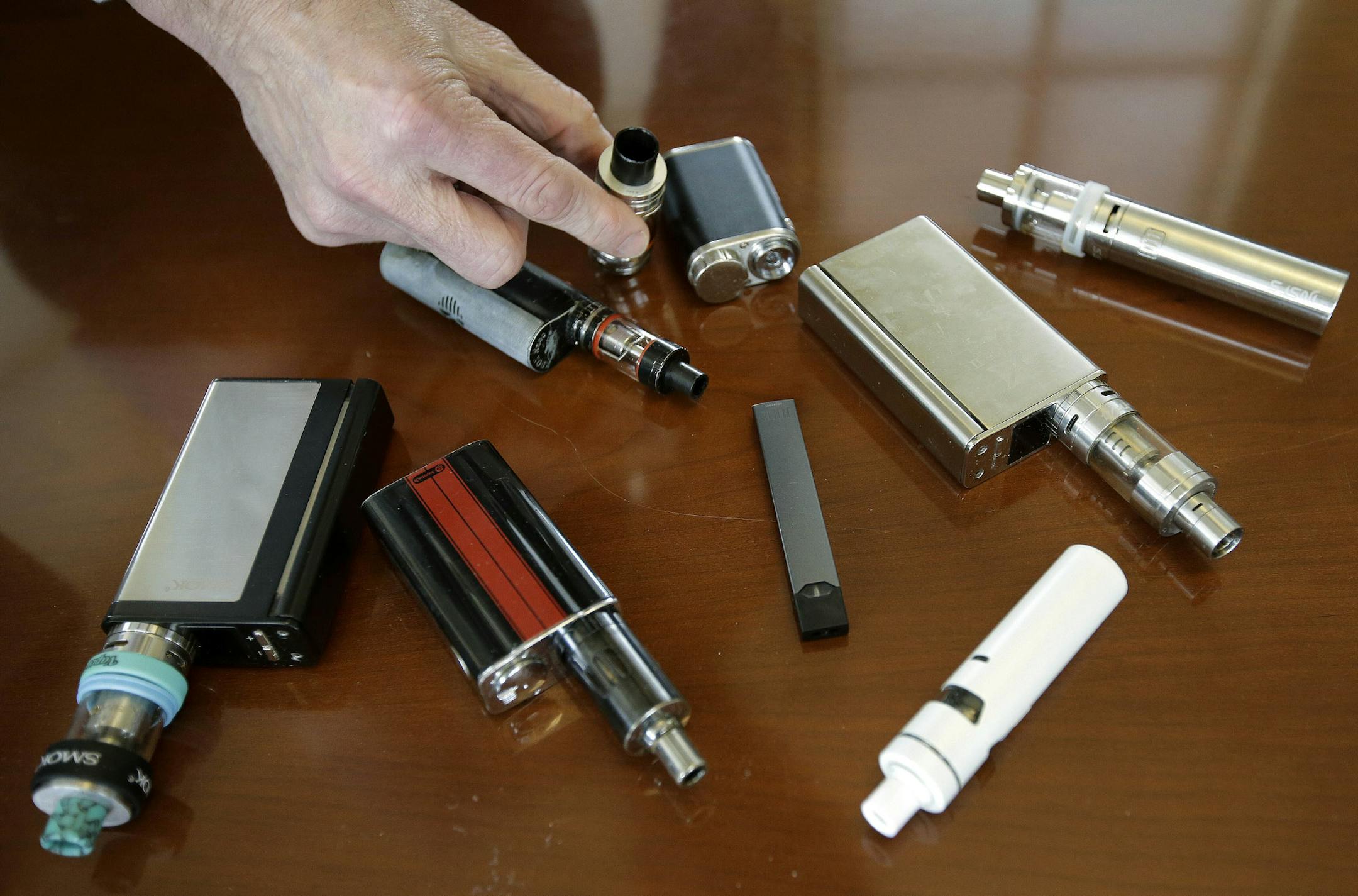 FILE - In this April 10, 2018, file photo, a high school principal displays vaping devices that were confiscated from students in such places as restrooms or hallways at the school in Massachusetts. With one in four teenagers now using electronic cigarettes, underage vaping is universally condemned, and the federal government considers it an epidemic. But some other researchers believe recent trends continue to show vaping’s promise as a tool to steer millions of adult smokers away from c
