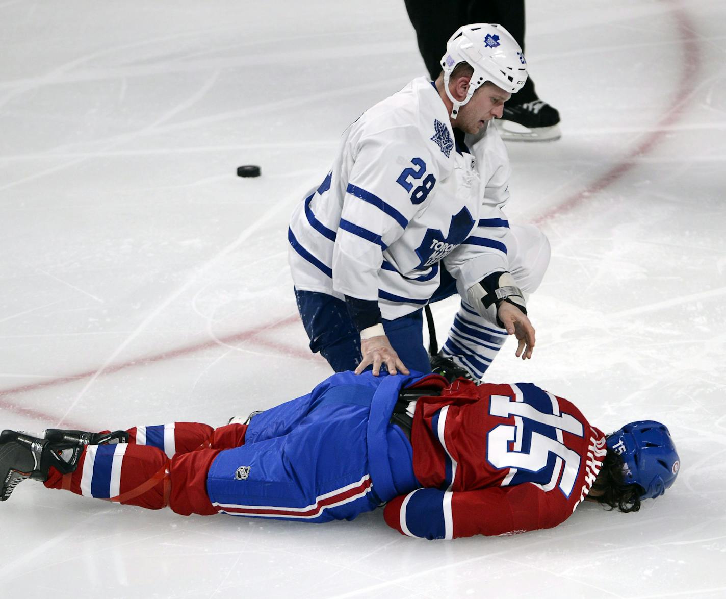 Toronto Maple Leafs right wing Colton Orr (28) kneels over Montreal Canadiens right wing George Parros (15) after Parros hit his head on the ice during their fight in the third period of an NHL hockey game on Tuesday, Oct. 1, 2013, in Montreal. (AP Photo/The Canadian Press, Ryan Remiorz)