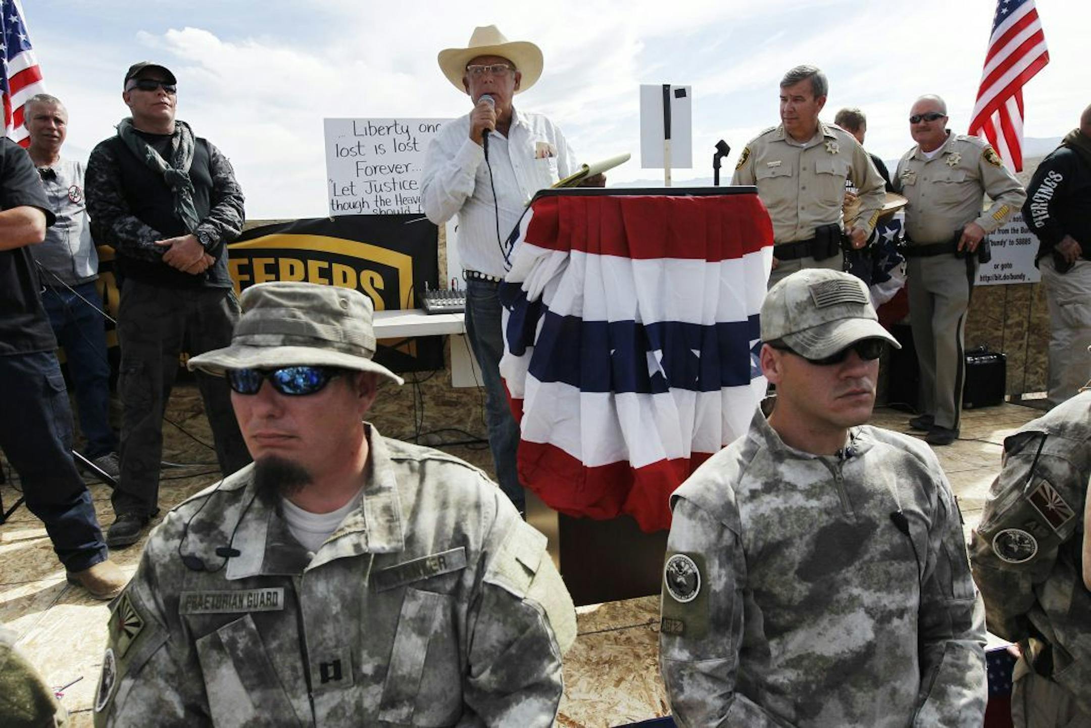 File-This April 12, 2014 file photo shows Rancher Cliven Bundy, center, addressing his supporters along side Clark County Sheriff Doug Gillespie, right, while being guarded by self-described militia members in the foreground.