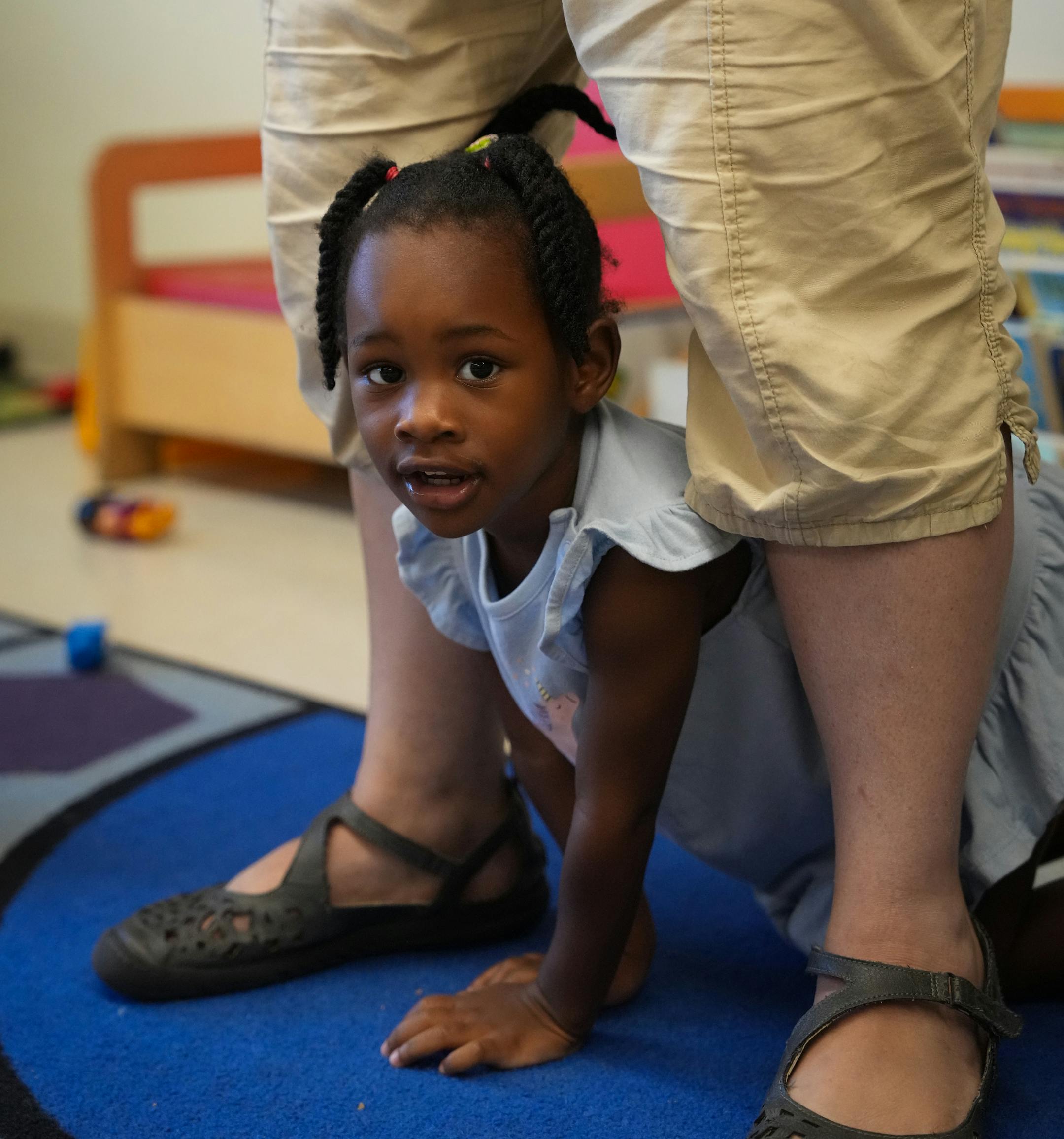 A student crawls through the legs of teacher Idelle Keding in the class of two-year-olds.