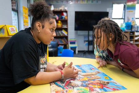 Elsie Carmona Quiterio, an education specialist, works on reading skills with Aasyeya, a first-grade student, at Phelps Recreation Center in Minneapol