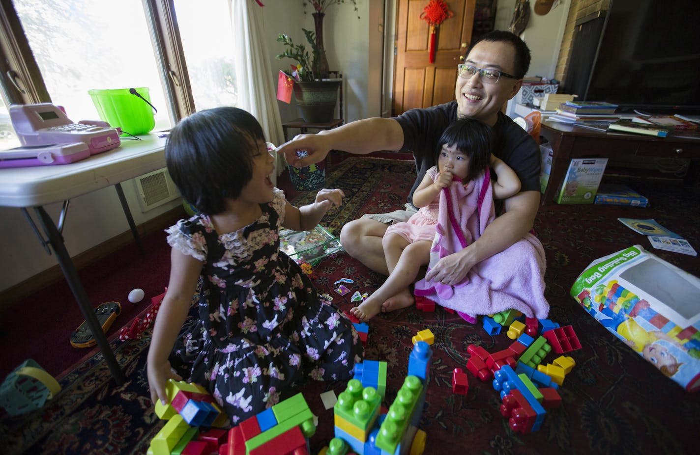 Ji Li plays with his daughters Manda, left, 4, and Jillian, 2, after work.