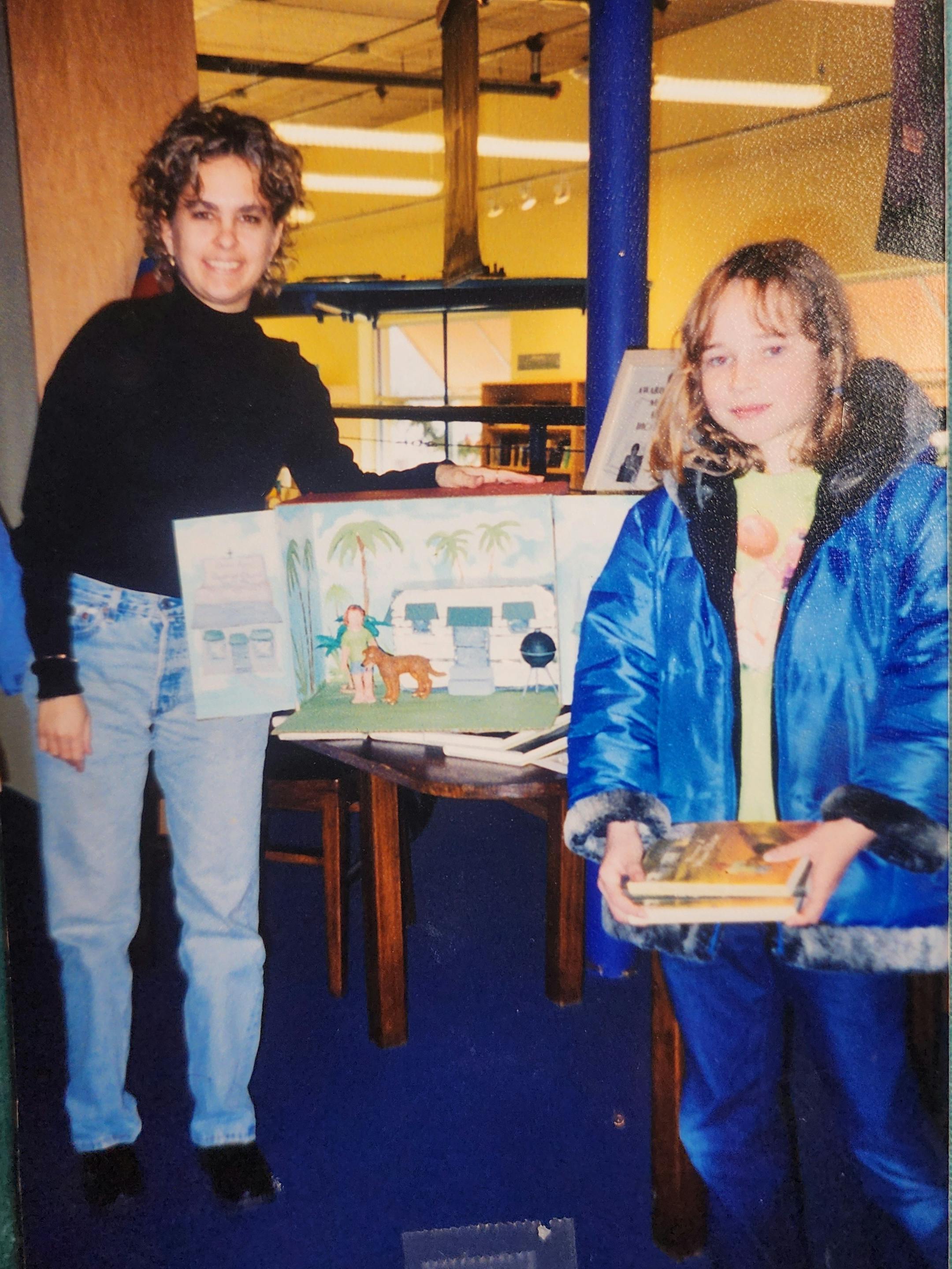 photo of a girl and a woman, with a diorama that depicts a girl and her dog