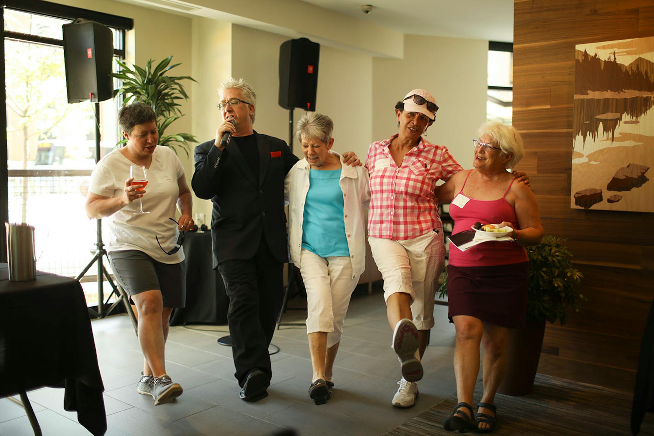 Kathy Flagge, Jane Holmes, Wanda Ortiz, and Barbara Saunders, from left, danced with Gary LaRue as he sang "New York, New York" during the open house at Abiitan Mill City. Ortiz already lives in the neighborhood a few blocks away and was trying to convince her friend Flagge and her partner to move downtown.