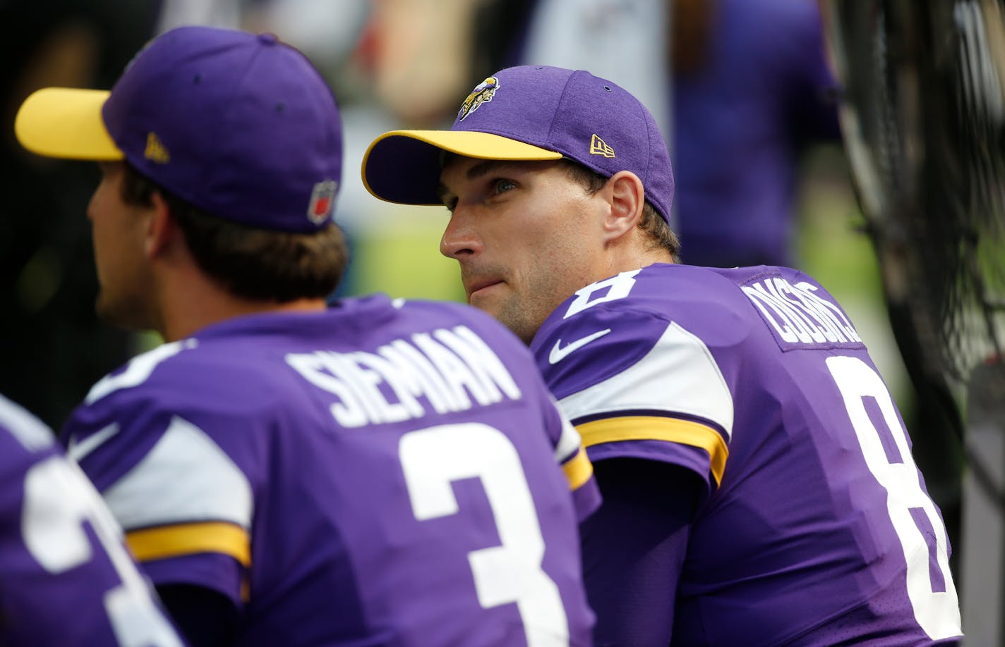 Minnesota Vikings quarterback Kirk Cousins, right, sits on the bench with teammate Trevor Siemian