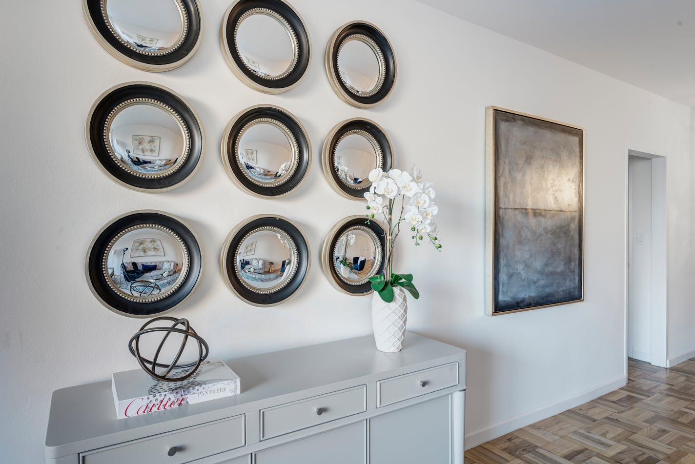 Nine small circular mirrors arranged in rows of three on a wall.