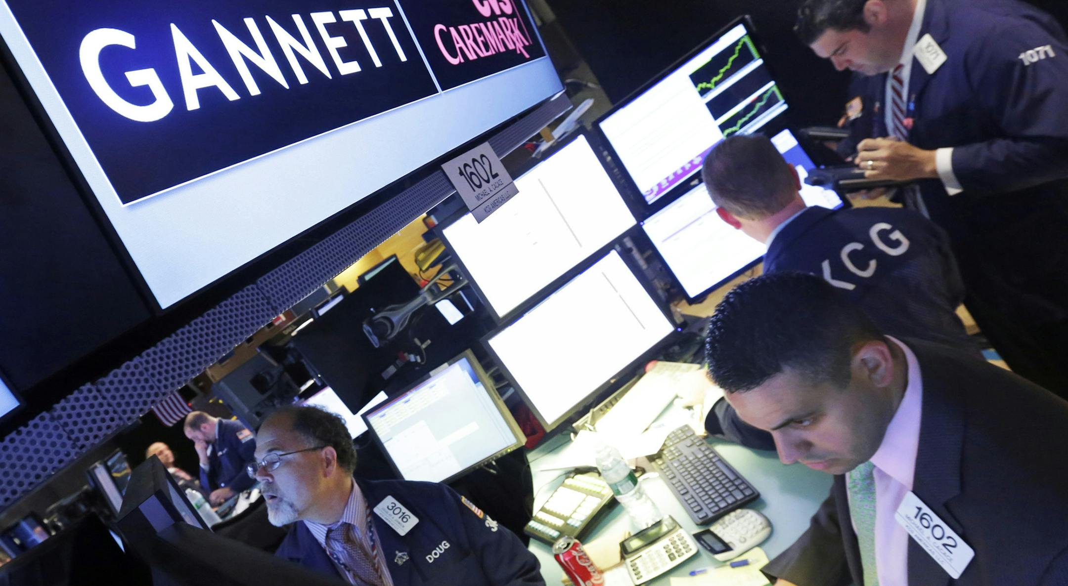 FILE - In this Aug. 5, 2014, file photo, specialist Michael Cacace, foreground right, works at the post that handles Gannett on the floor of the New York Stock Exchange. The Wall Street Journal is reporting that MNG Enterprises, better known as Digital First Media, is preparing to bid for newspaper publisher Gannett Co. (AP Photo/Richard Drew, File)