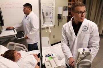 Matthew Girtz, right, and Andrew Hutton worked with instructor Tracy Moshier who was acting as a patient during a simulated situation in the nursing s