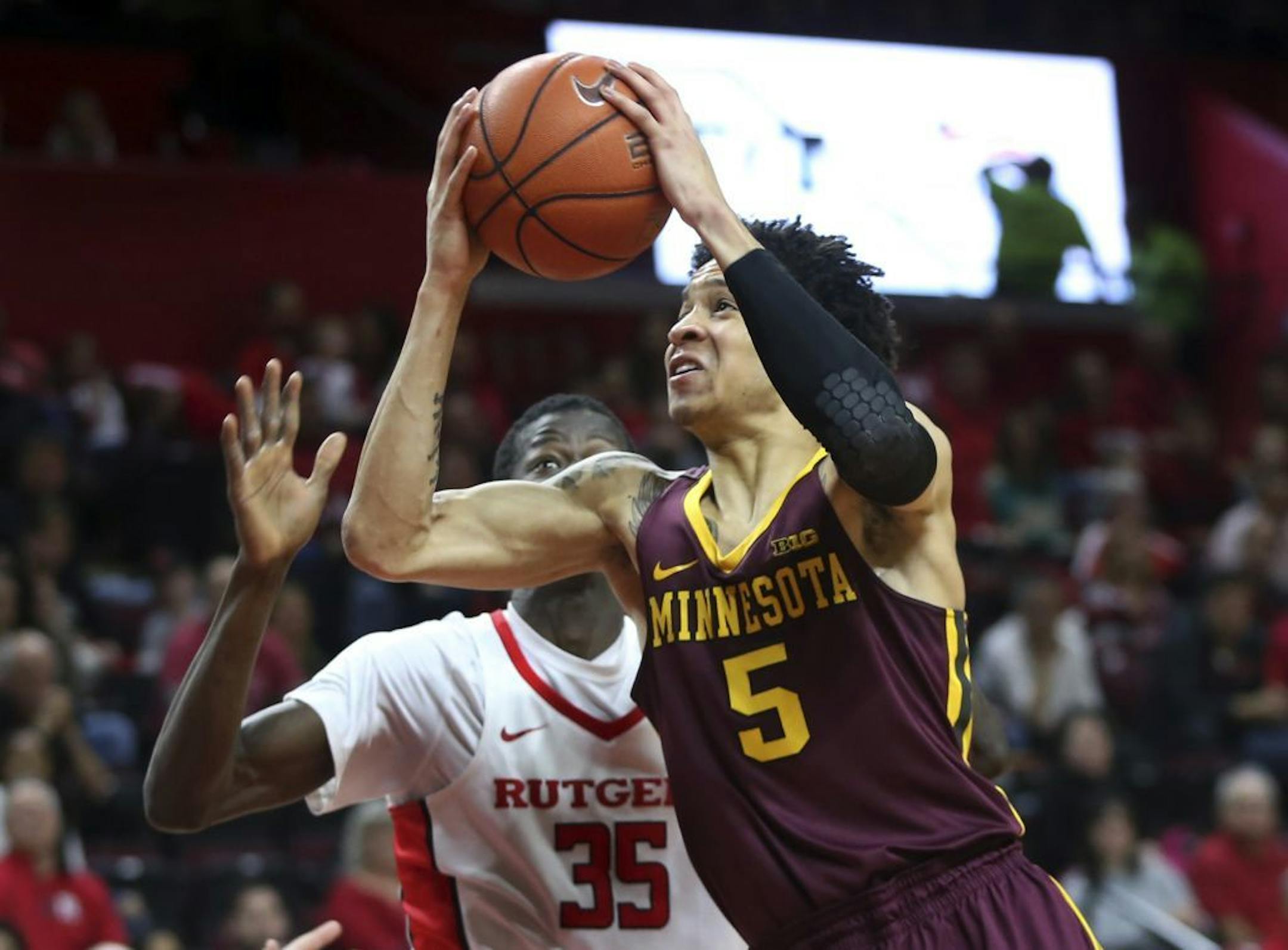 Minnesota guard Amir Coffey (5) looks to take a shot past Rutgers forward Issa Thiam, (35) of Senegal, during the first half of an NCAA college basketball game, Saturday, Feb. 11, 2017, in Piscataway, N.J.
