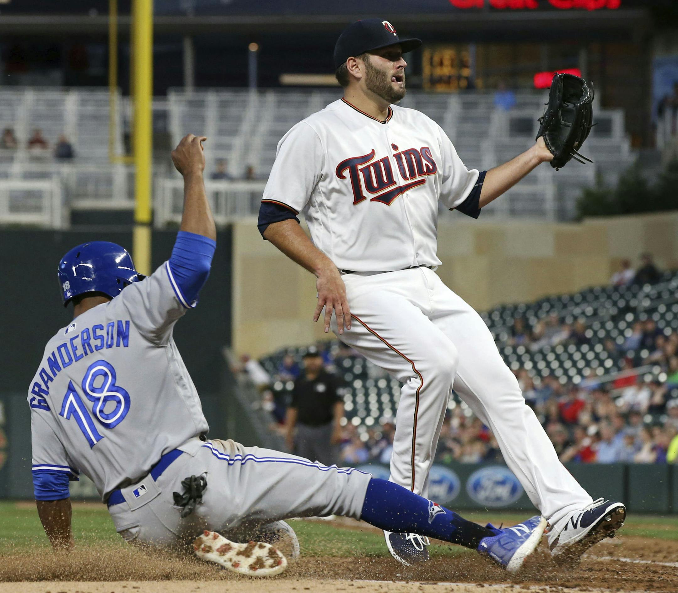 Toronto Blue Jays' Curtis Granderson, left, scores past Minnesota Twins pitcher Lance Lynn on a passed ball by Lynn in the fourth inning of a baseball game Monday, April 30, 2018, in Minneapolis. (AP Photo/Jim Mone)