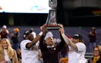 Minnesota defensive back Tyler Nubin, left, coach P.J. Fleck and running back Ky Thomas hold up the trophy after Minnesota defeated West Virginia 18-6