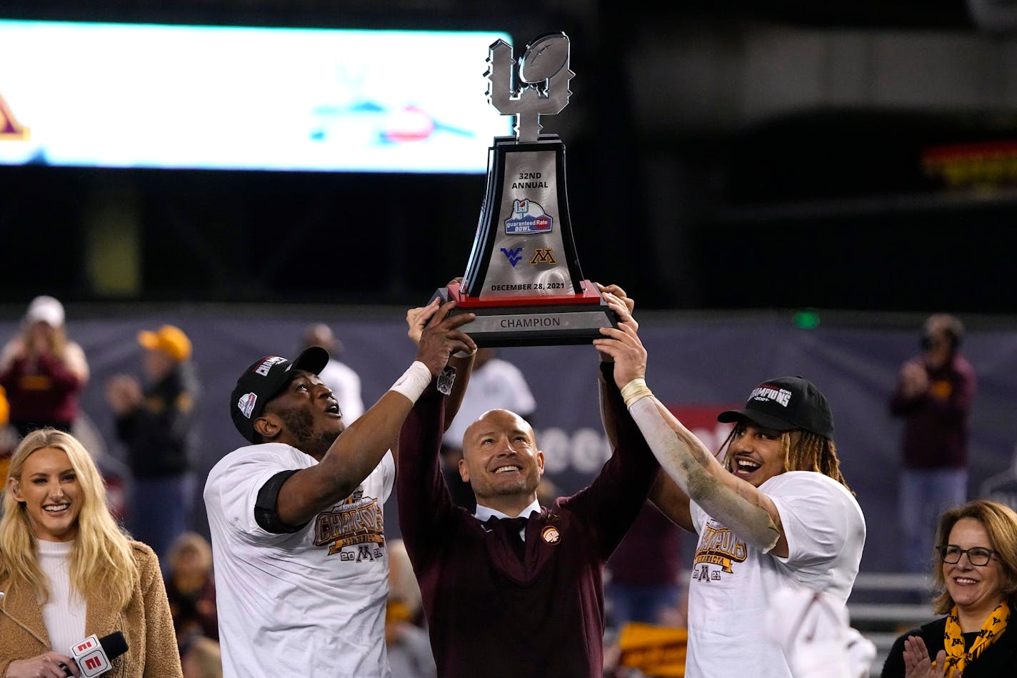 Minnesota defensive back Tyler Nubin, left, coach P.J. Fleck and running back Ky Thomas hold up the trophy after Minnesota defeated West Virginia 18-6 in the Guaranteed Rate Bowl NCAA college football game Tuesday, Dec. 28, 2021, in Phoenix. (AP Photo/Rick Scuteri)