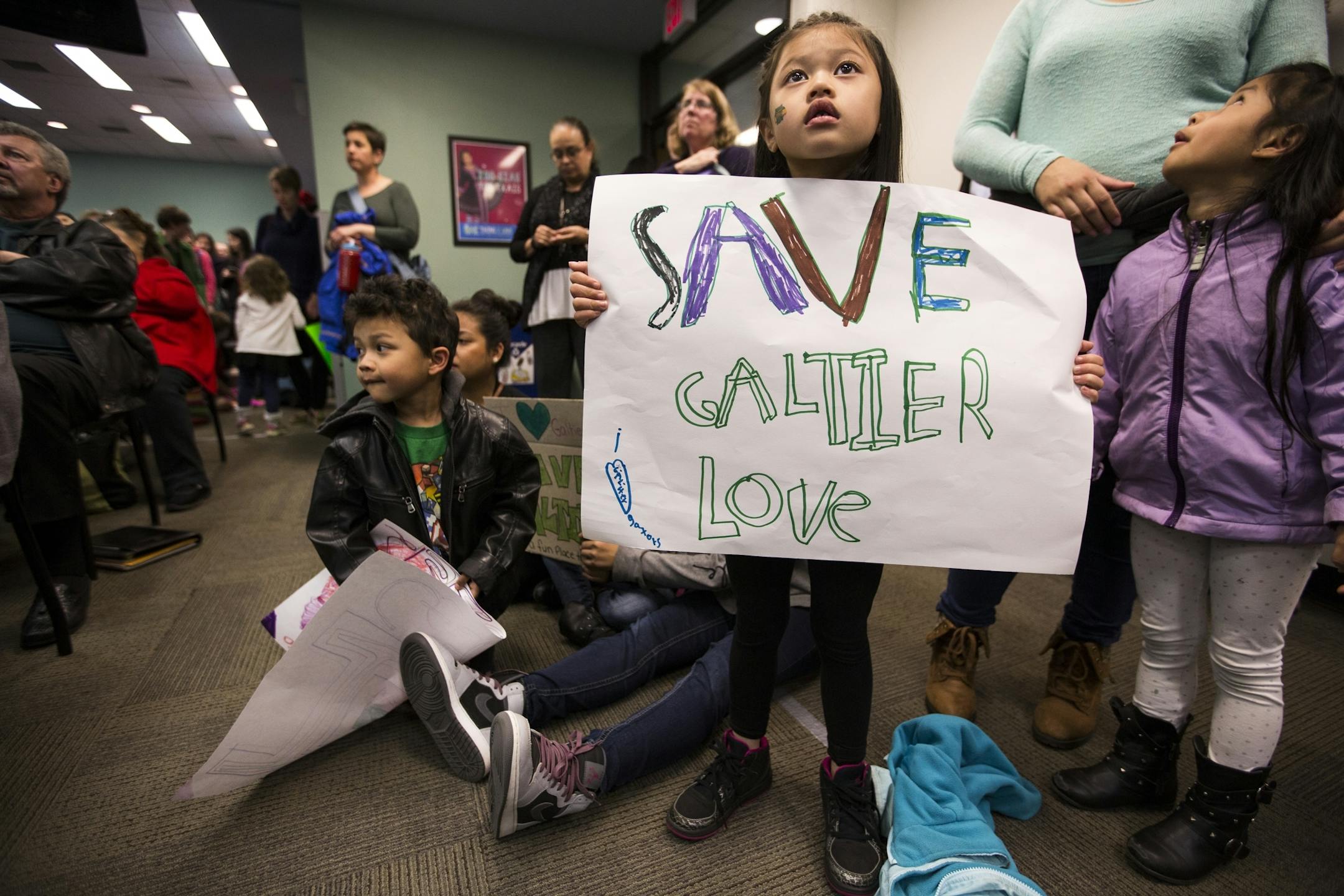 Galtier Community School pre-kindergarten student Emiliya Daoheuang, 5, holds a sign during the public comment portion of a St. Paul School Board meeting.
