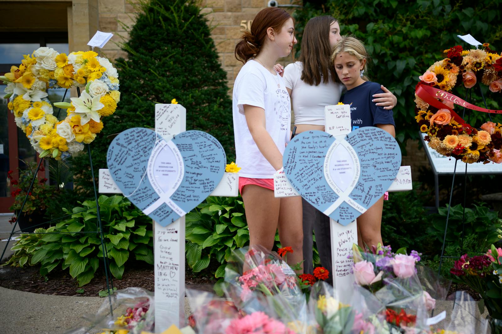 Lulu, 12, center, a former Annunciation student, and her friends and current students Cora, 12, left, and Astoria Safe, 10, visit the memorial Thursday for their classmates who were shot and killed in the church.