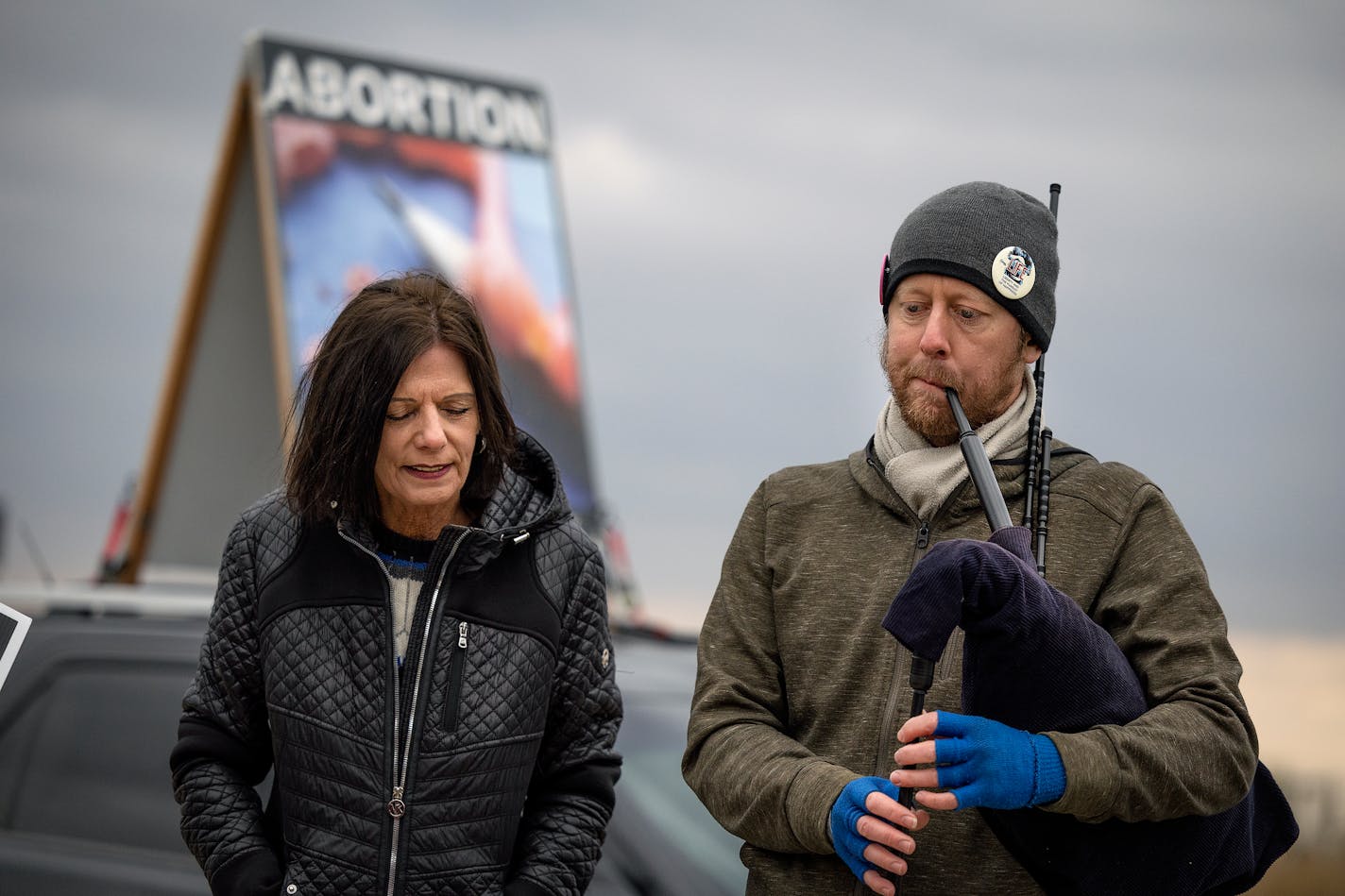 Abortion opponent Jody Clemens, left, listened as pastor Paul Letvin of Submerge Church played "Amazing Grace" on bagpipes outside the Red River Women's Clinic in Moorhead.