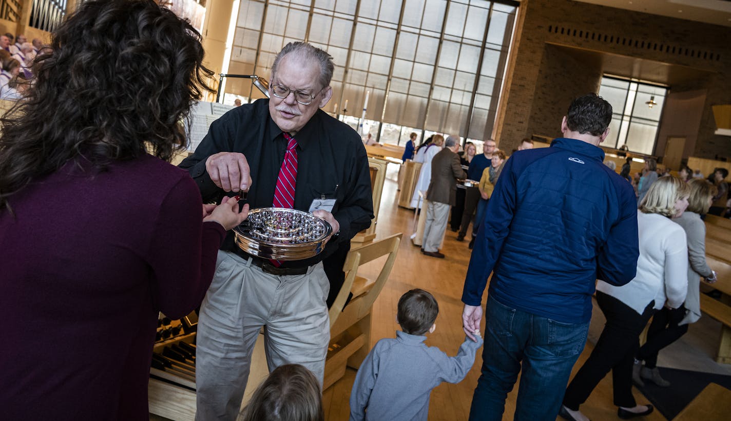 Harold Kingsbury served communion wine in small plastic cups instead of a communal chalice.] St Andrew's Church is serving communion wine in tiny plastic cups this weekend, instead of a in chalice, and parishioners are giving a "holy nods" to each other instead of handshakes or hugs.] RICHARD TSONG-TAATARII &#xa5; richard.tsong-taatarii@startribune.com