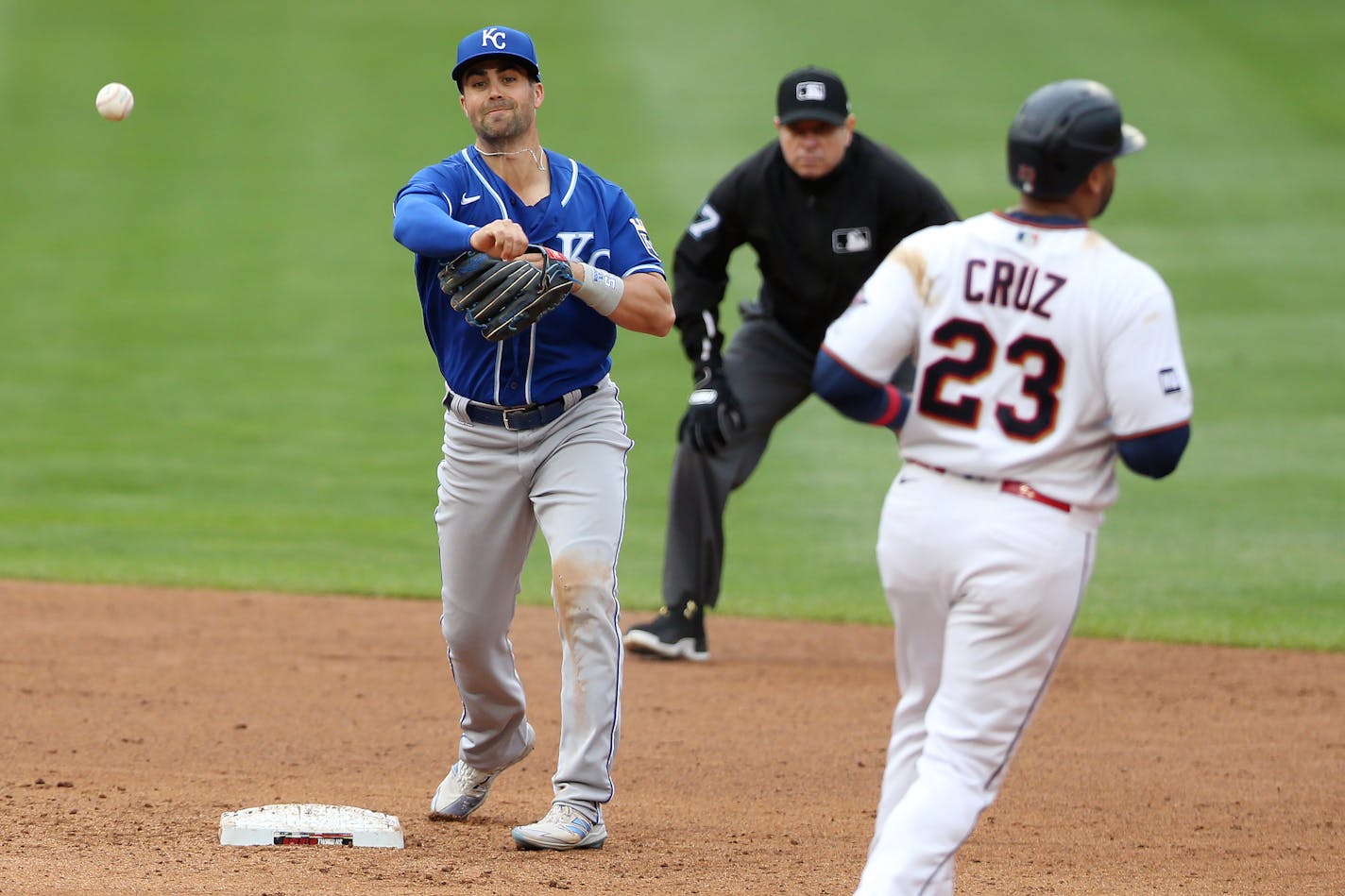 Kansas City Royals' Whit Merrifield (15) throws to first baseman Carlos Santana for a double play after getting Minnesota Twins' Nelson Cruz (23) out at second during the fifth inning of a baseball game Sunday, May 30, 2021, in Minneapolis. (AP Photo/Stacy Bengs)