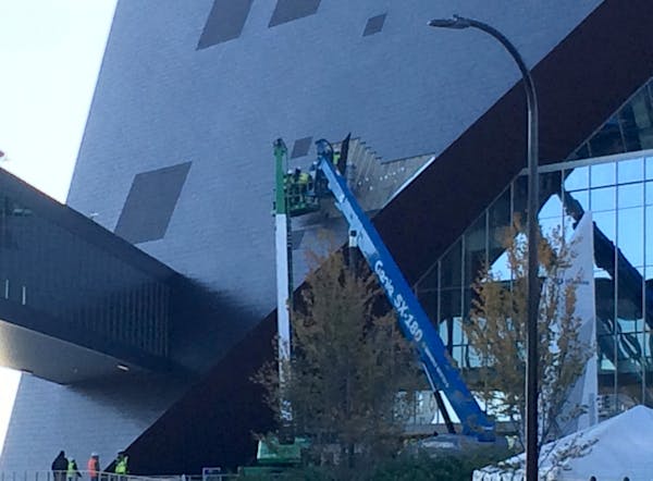 Workers examined the exterior of U.S. Bank Stadium with some of the zinc panels removed Thursday morning on the north side of the stadium.