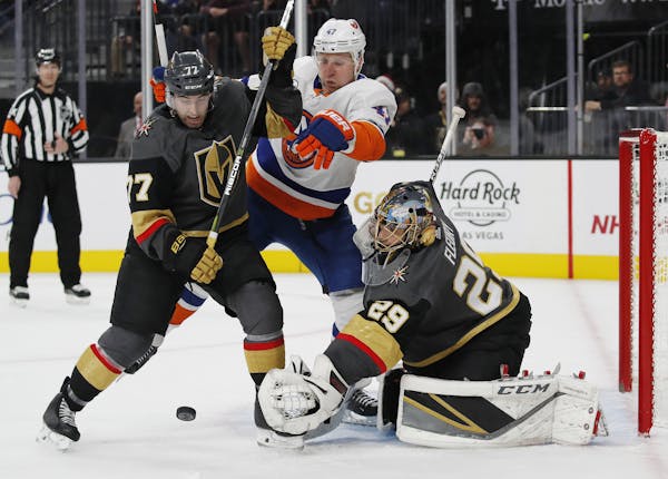 Vegas Golden Knights defenseman Brad Hunt (77) and New York Islanders right wing Leo Komarov (47) vie for the puck as Golden Knights goaltender Marc-A