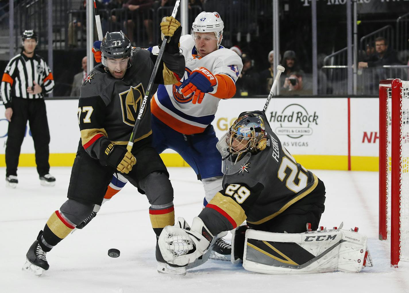 Vegas Golden Knights defenseman Brad Hunt (77) and New York Islanders right wing Leo Komarov (47) vie for the puck as Golden Knights goaltender Marc-Andre Fleury (29) blocks a shot during the third period of an NHL hockey game Thursday, Dec. 20, 2018, in Las Vegas. (AP Photo/John Locher)