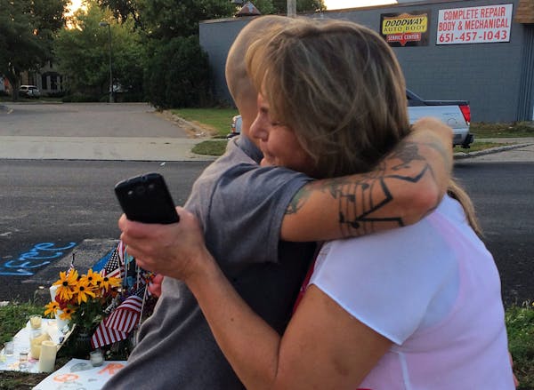 Jason Serbesku hugs a woman who came by to thank him for tending the memorial to slain Mendota Heights police officer Scott Patrick.