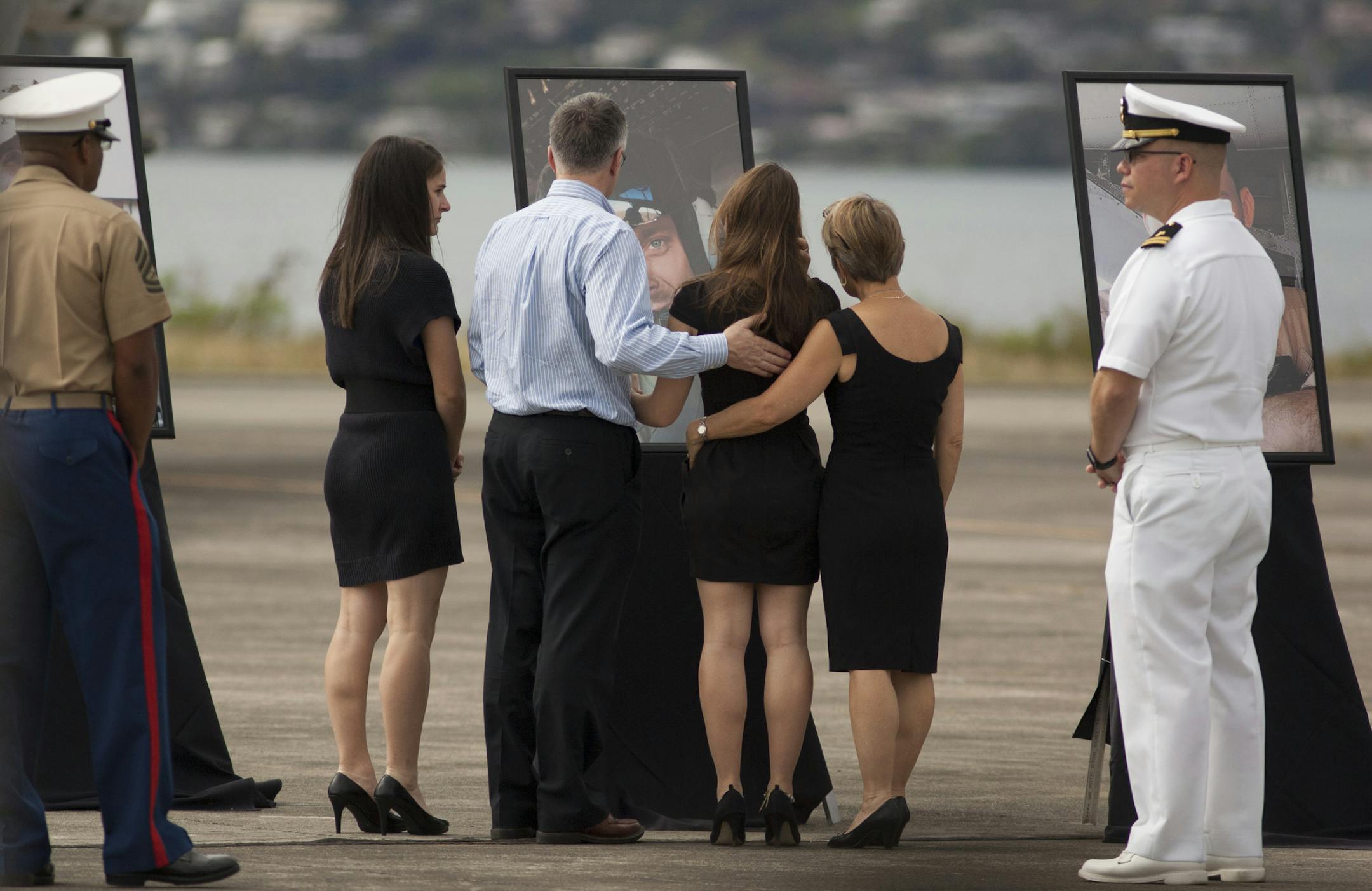 Unidentified family members gather around a photograph of U.S. Marine Sgt. Dillon J. Semolina, 24, of Chaska Minnesota during a memorial service for the 12 Marines who died when their helicopters crashed off the North Shore of Oahu, Hawaii, Friday Jan. 22, 2016, at Marine Corps Base Hawaii. Servicemen draped flight gear on 12 white crosses Friday to commemorate the Marines who died when two helicopters crashed off the coast of Hawaii during a nighttime training mission. Military members and fami