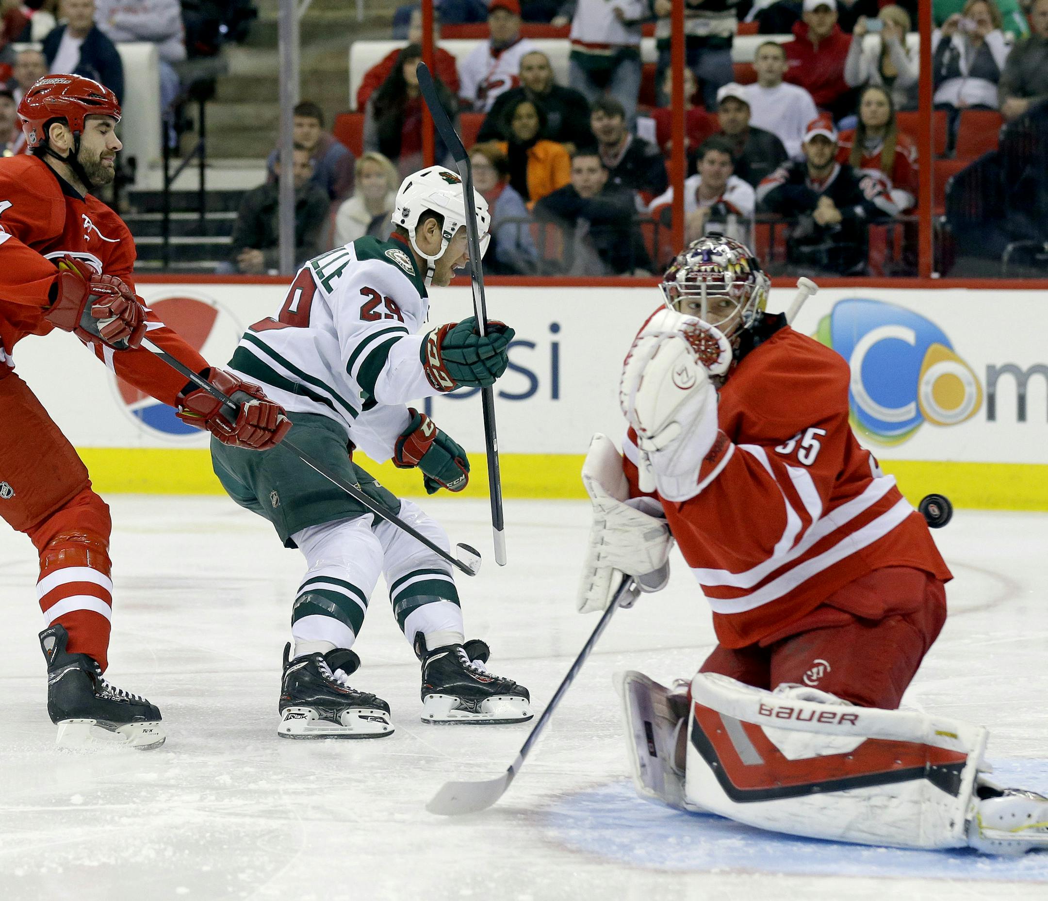 Carolina Hurricanes' Jay Harrison (44) defends as Minnesota Wild's Jason Pominville (29) scores on Hurricanes goalie Justin Peters (35) during the first period of an NHL hockey game in Raleigh, N.C., Saturday, Nov. 9, 2013. (AP Photo/Gerry Broome)