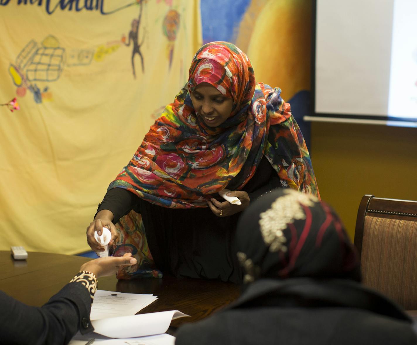 Farhiya Farah handed out lotion, above, to test hand-washing effectiveness with a black light, top, with students in her food-safety class, taught in Somali.