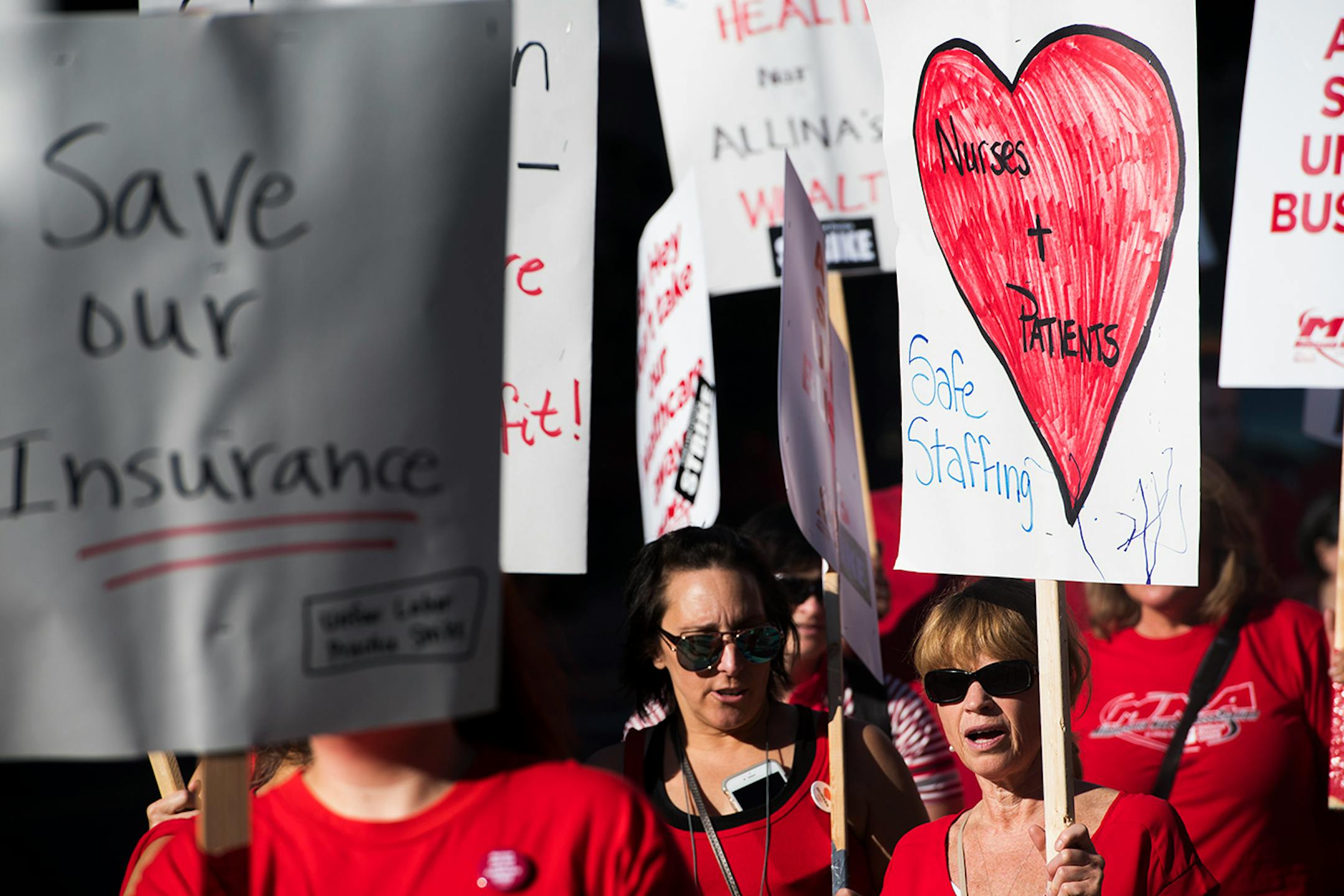 Chris Ayde, left, and Jessica Groppoli walk with signs along the picket line in front of United Hospital in St. Paul.