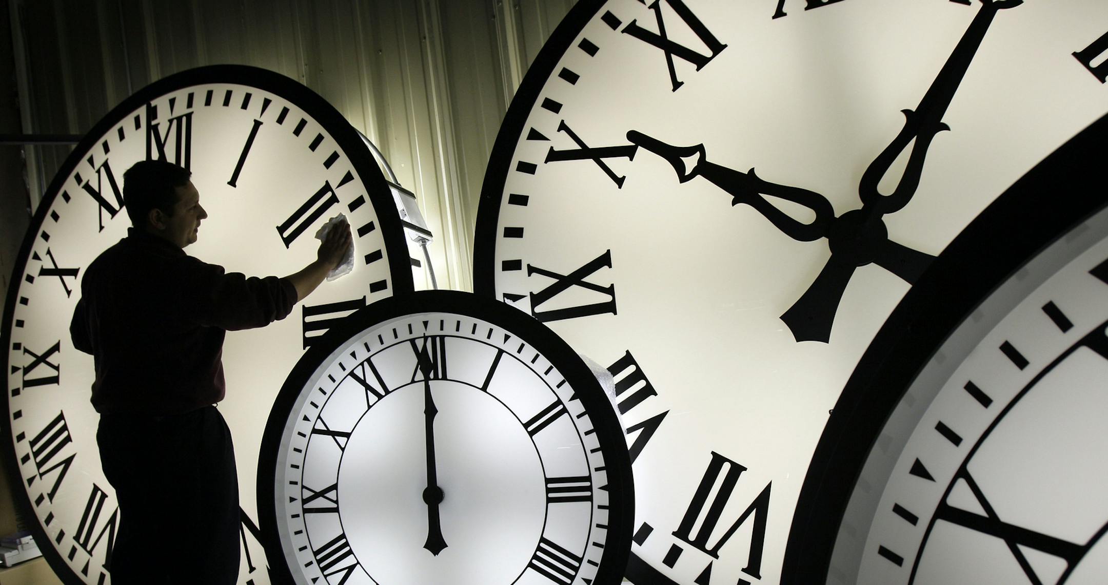 Electric Time Co. employee Walter Rodriguez cleans the face of an 84-inch Wegman clock at the plant in Medfield, Mass. Thursday, Oct. 30, 2008. Daylight savings time ends early Sunday morning with clocks turned back one hour. (AP Photo/Elise Amendola) ORG XMIT: MIN2013030815590138