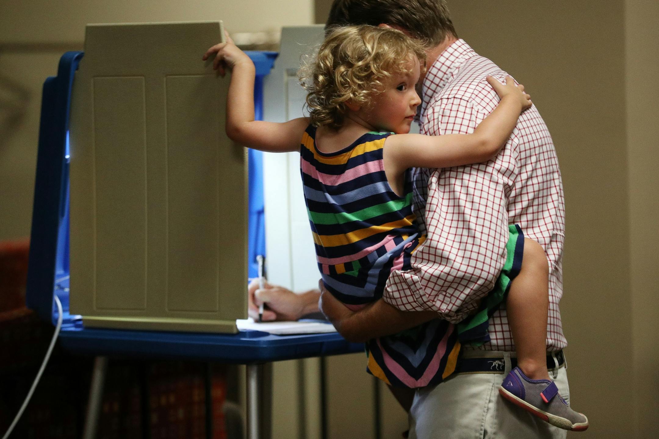 Clare Craig, 3, held onto her dad Pat as he cast his ballot on primary election day at Holy Spirit Catholic Church in St. Paul.