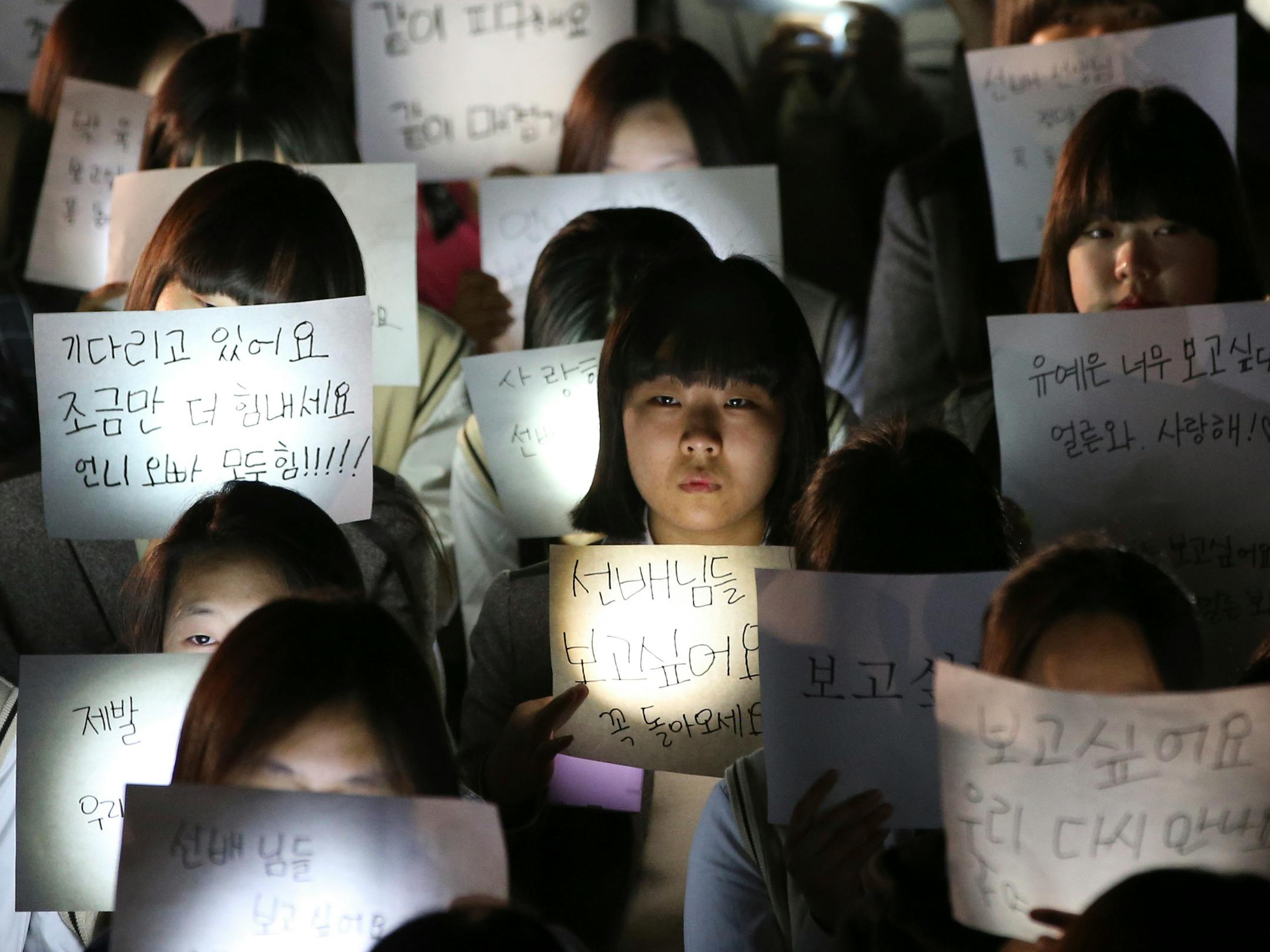 Students hold papers with candles as they pray for the safe return of their friends aboard the sunken ferry Sewol at Danwon High School in Ansan, south of Seoul, South Korea, Friday, April 18, 2014. Rescuers scrambled to find hundreds of ferry passengers still missing Friday and feared dead in the waters off the country's southern coast, as fresh questions emerged about whether quicker action by the captain of the doomed ship could have saved lives. (AP Photo/Yonhap) KOREA OUT