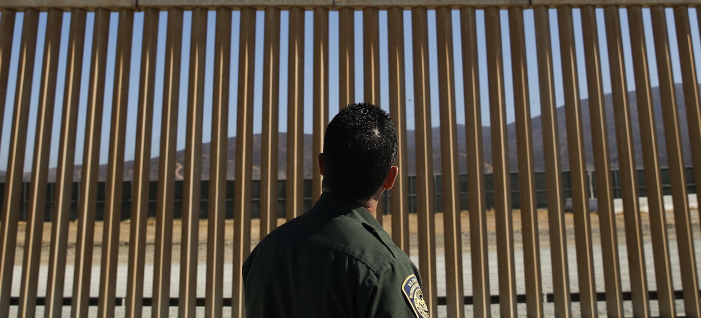 A U.S. Border Patrol agent looks at one of border wall prototypes Thursday, June 28, 2018, in San Diego. (AP Photo/Jae C. Hong, File) ORG XMIT: MIN2018081511515511