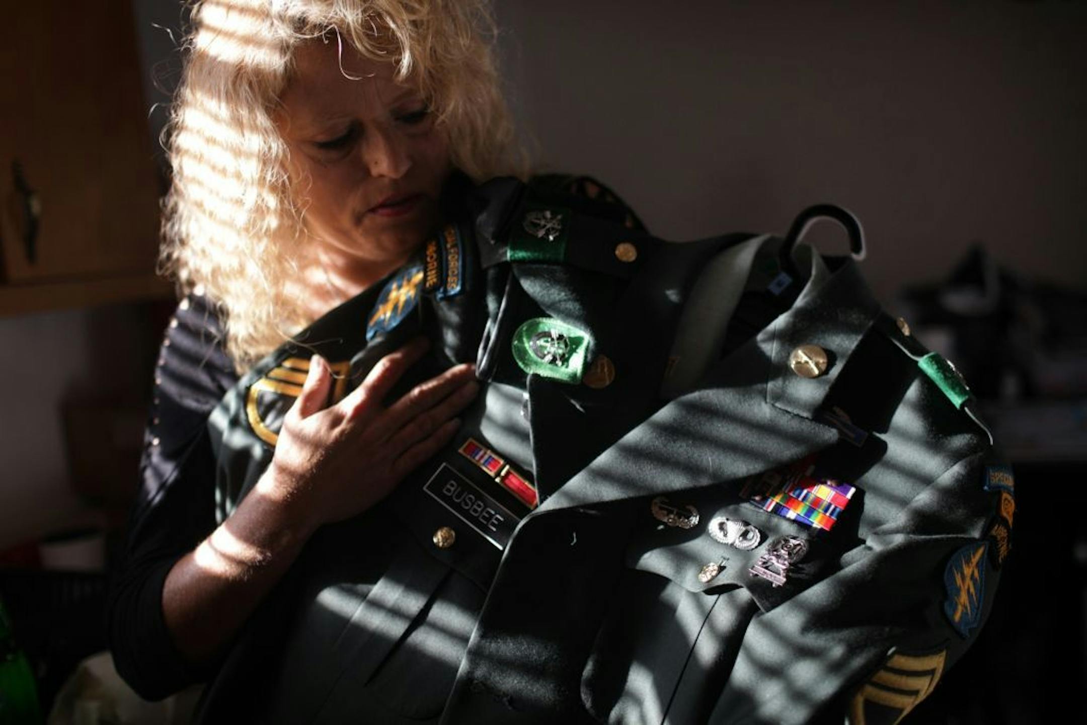 In an Oct. 10, 2012 photo, Libby Busbee holds her son U.S. Army Spc. William Busbee's uniform in her kitchen in Panama City, Fla. Spc. Busbee committed suicide using a gun in March.