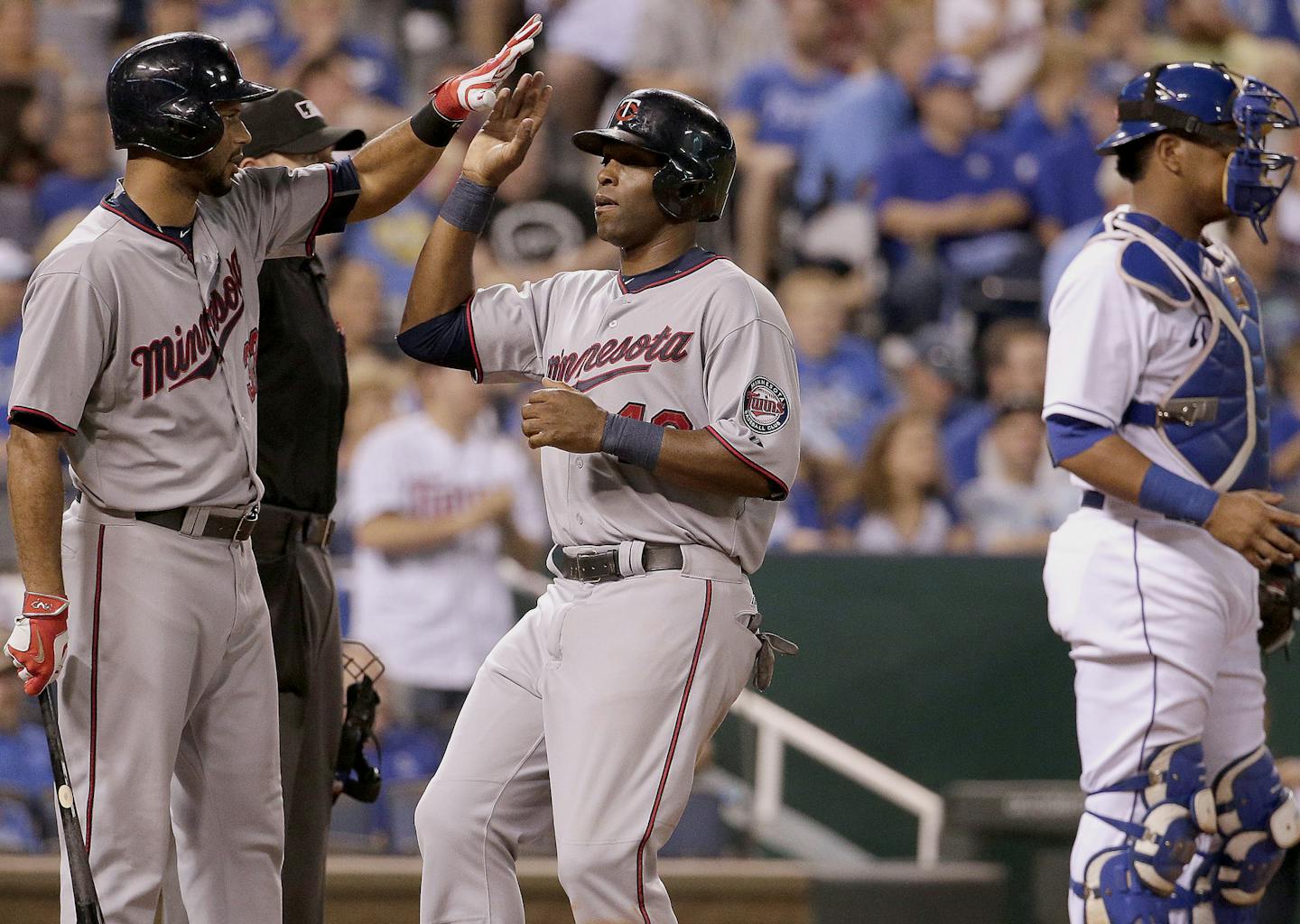 Minnesota Twins' Torii Hunter, center, celebrates with Aaron Hicks after Hunter scored on a single by Eduardo Escobar during the sixth inning of a baseball game against the Kansas City Royals, Monday, Sept. 7, 2015, in Kansas City, Mo. (AP Photo/Charlie Riedel)