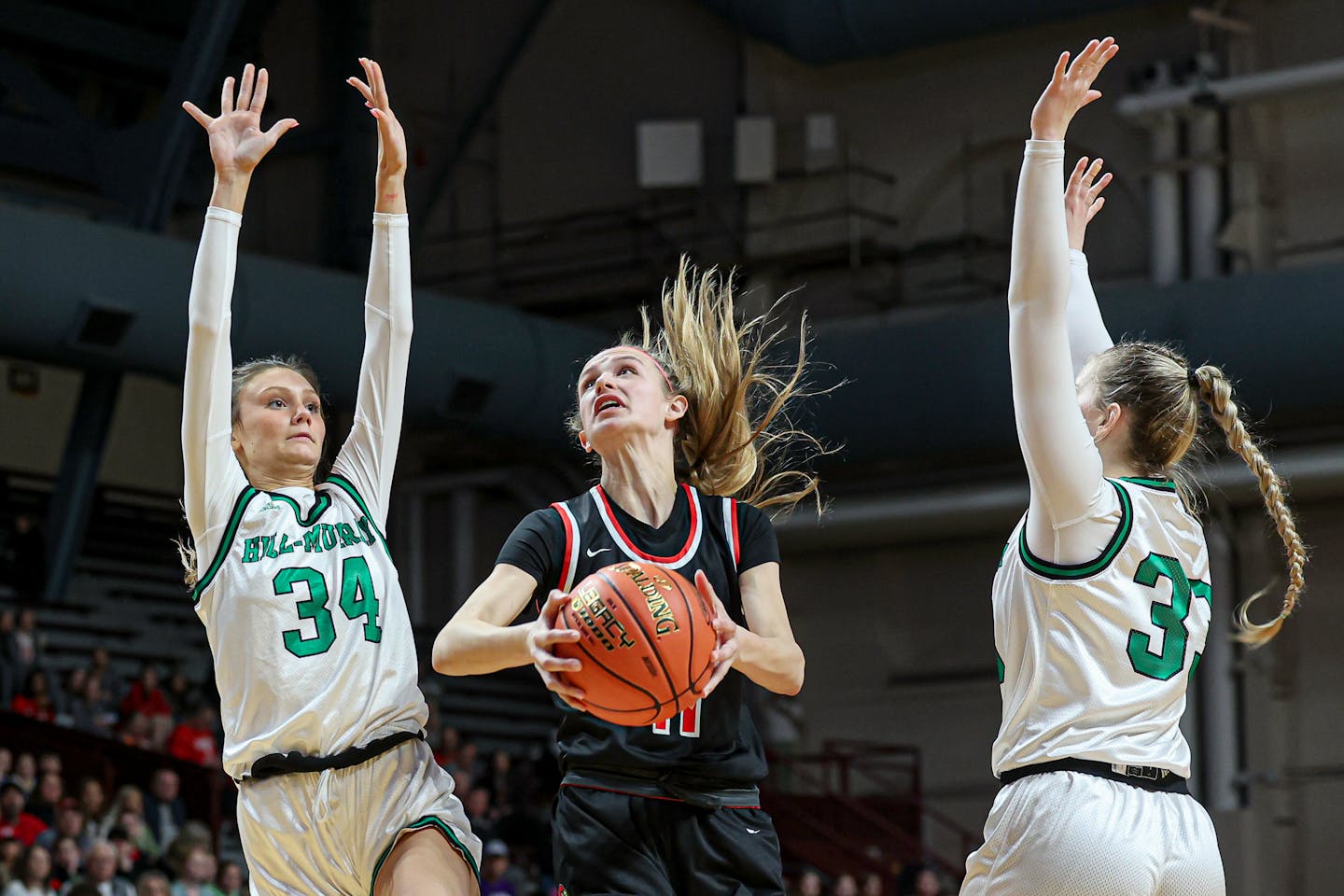 Hadley Thul (11) of Alexandria went between Hill-Murray defenders Emma Vaske (34) and Payton Mackley (33) for a second-half basket in the Cardinals' 57-39 victory in a Class 3A state tournament quarterfinal at Maturi Pavilion. Thul had a game-high 18 points. Class 3A girls basketball state tournament quarterfinal, Hill-Murray vs. Alexandria, 3-15-23. Photo by Mark Hvidsten, SportsEngine