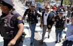 FILE - In this Tuesday, July 19, 2016 file photo, Alex Jones, center right, is escorted by police out of a crowd of protesters outside the Republican 