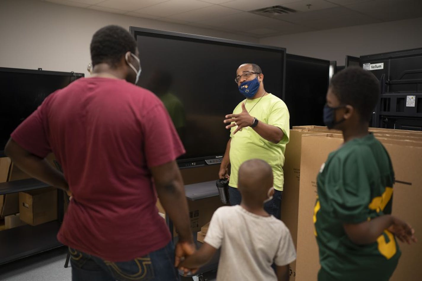 Friendship Academy of the Arts Executive Director, B. Charvez Russell, right, explained to returning parent Ile Lakte how the new Promethean boards will be used in classrooms to enhance distance learning. Lakte's two boys, William, right, and David attend the school.