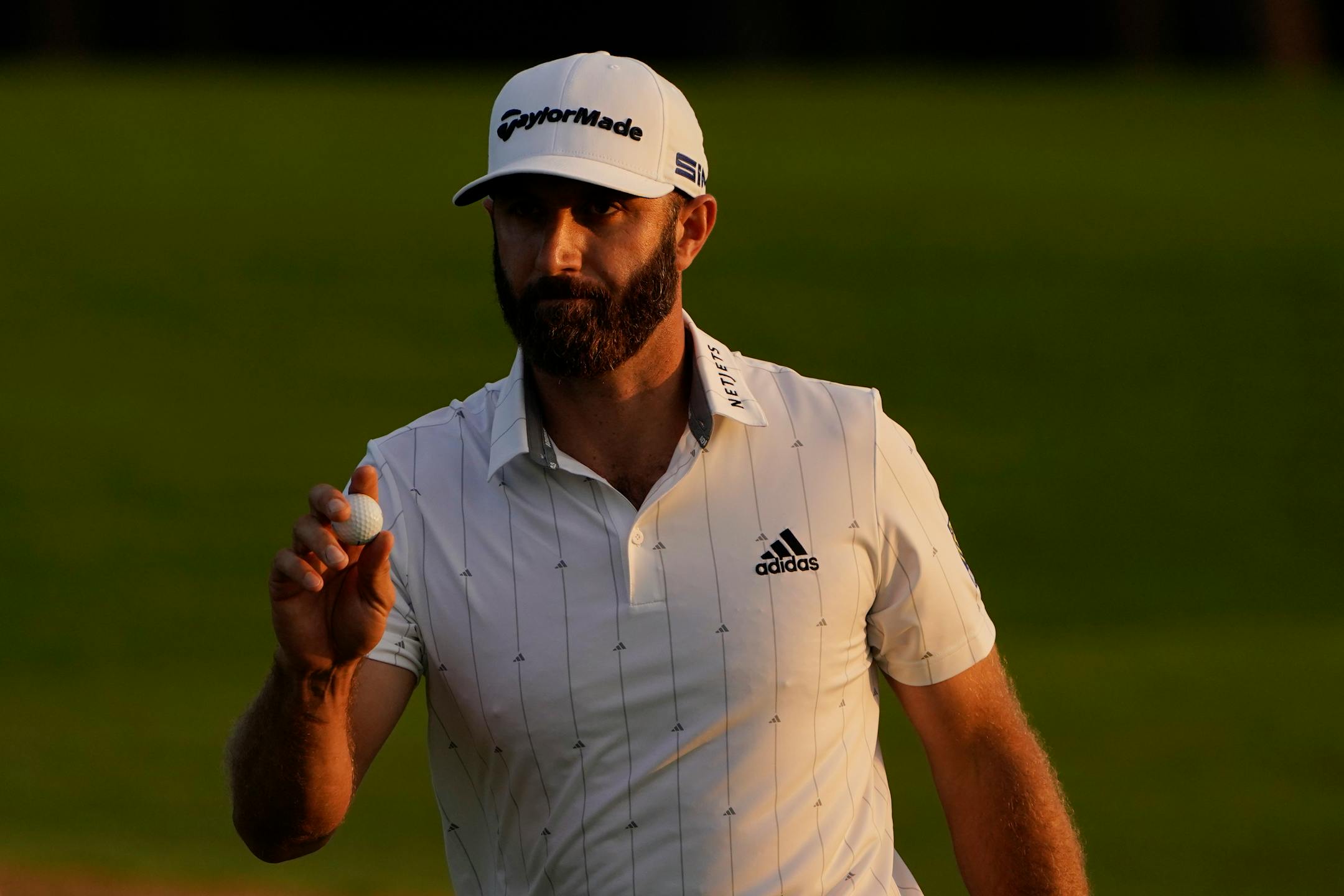 Dustin Johnson holds up his ball on the 18th green after his third round of the Masters golf tournament Saturday, Nov. 14, 2020, in Augusta, Ga. (AP Photo/Chris Carlson)