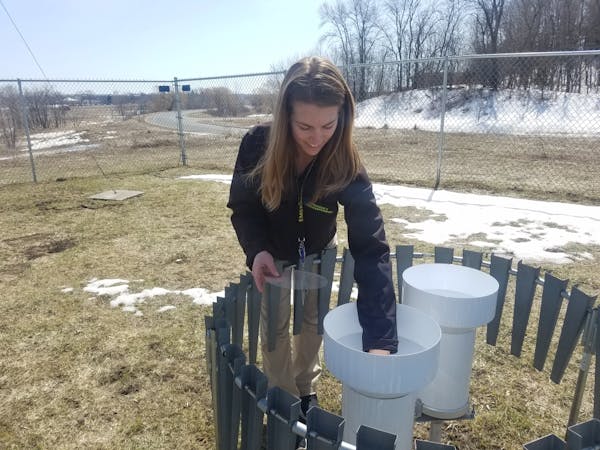 Emily Jackson, a meteorologist with Hennepin County Emergency Management, checks a rain gauge at weather station in Medina.