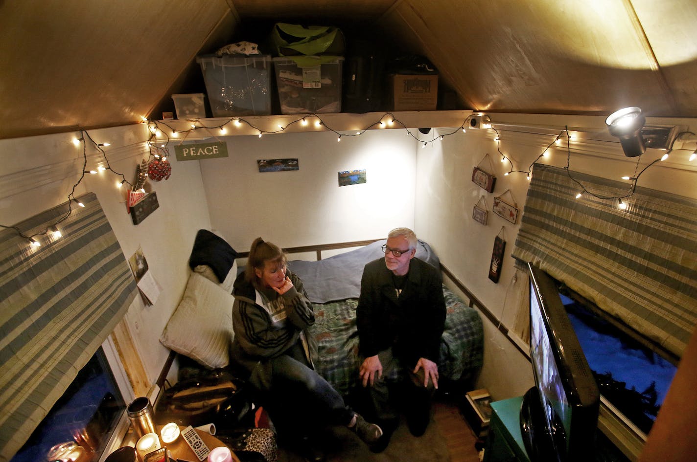 Four formerly homeless people, including a couple, have settled into a cluster of tiny houses they helped build in Madison along with members of Occupy Madison. Here, couple Betty Ybarra, 49, left, Chris Derek, 56, sit inside their tiny house in the OM village while enjoying candles and watching TV Tuesday, March 3, 2015, in Madison, WI.](DAVID JOLES/STARTRIBUNE)djoles@startribune.com Three men and a woman who once struggled with homelessness now live in a cluster of 100-square-foot houses that