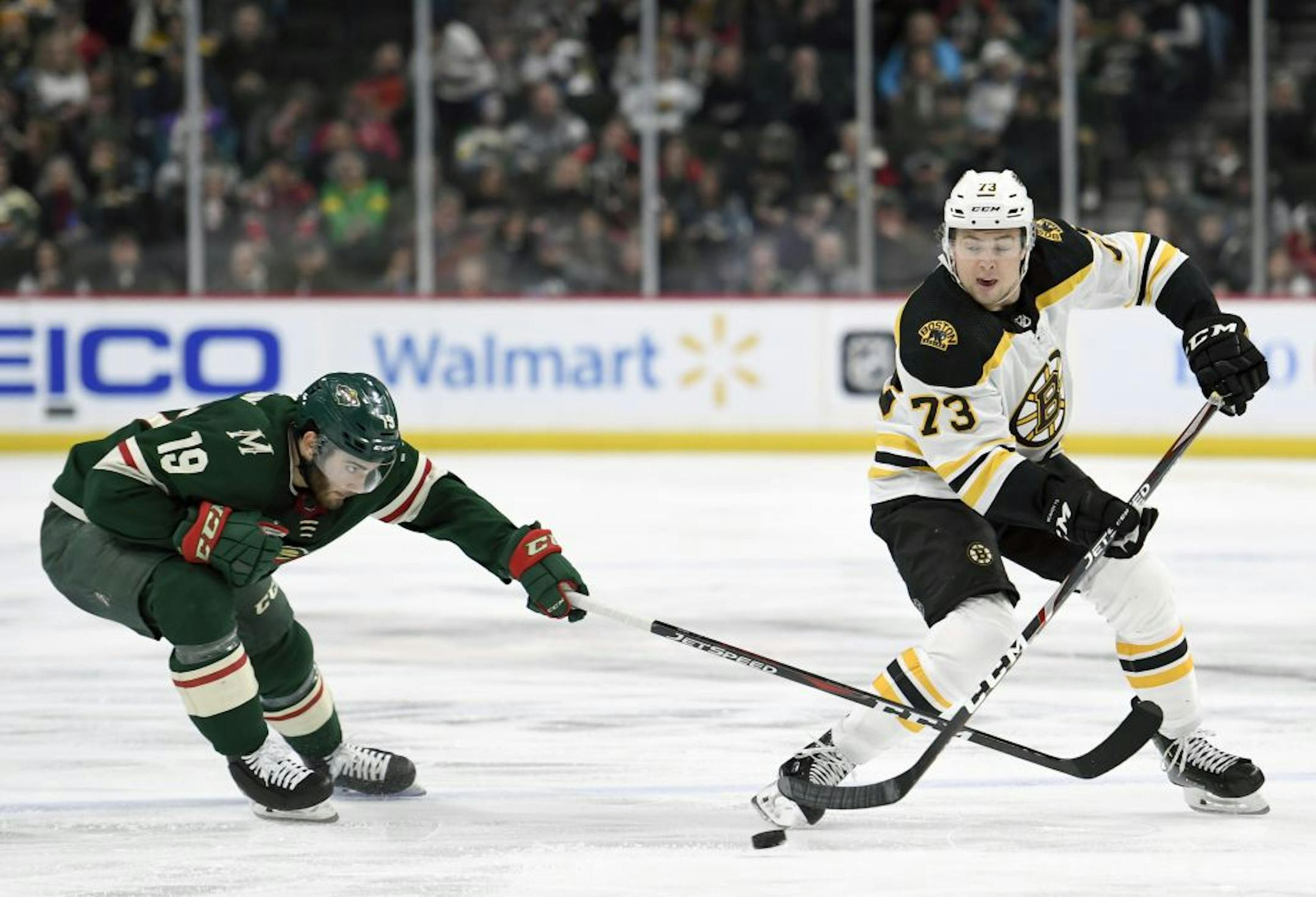 Boston Bruins' Charlie McAvoy (73) keeps the puck away from Minnesota Wild's Luke Kunin (19) during the second period of an NHL hockey game Saturday, Feb. 1, 2020, in St. Paul, Minn.