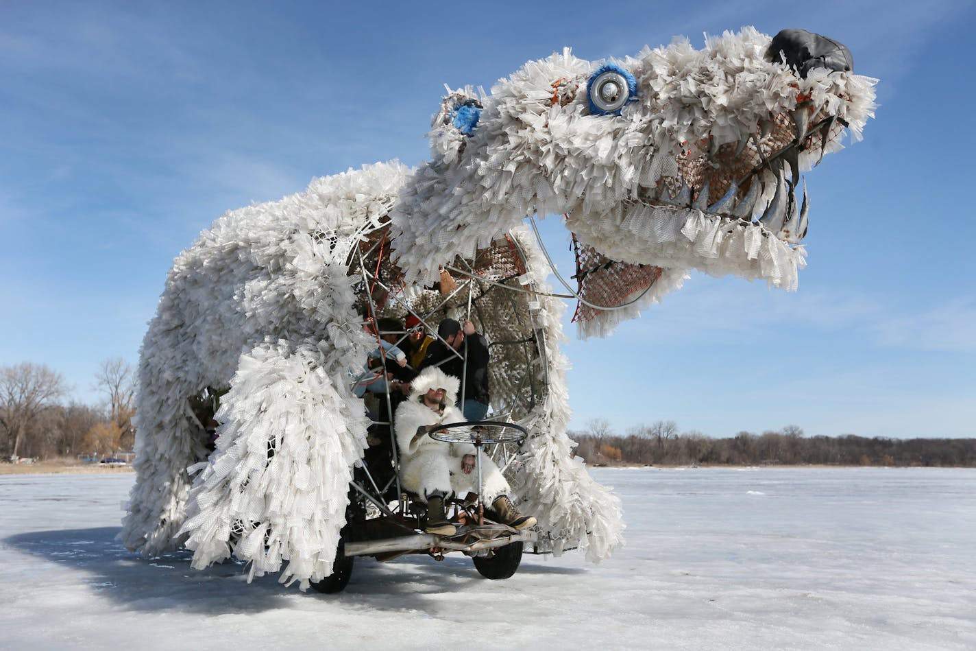 Riders climb aboard a 20-foot long, 12-foot high pedal-driven polar bear designed by Matoska Tonka Pedal Bears. Artist designed and built shanties were moved to the shore of White Bear Lake earlier this week after warm temperatures prompted the Department of Natural Resources to deem the ice unsafe for the structures. The Art Shanty Project is a month-long festival that takes place every February on White Bear Lake. ] (SHARI L. GROSS/STAR TRIBUNE) SHARI L. GROSS &#xef; sgross@startribune.com