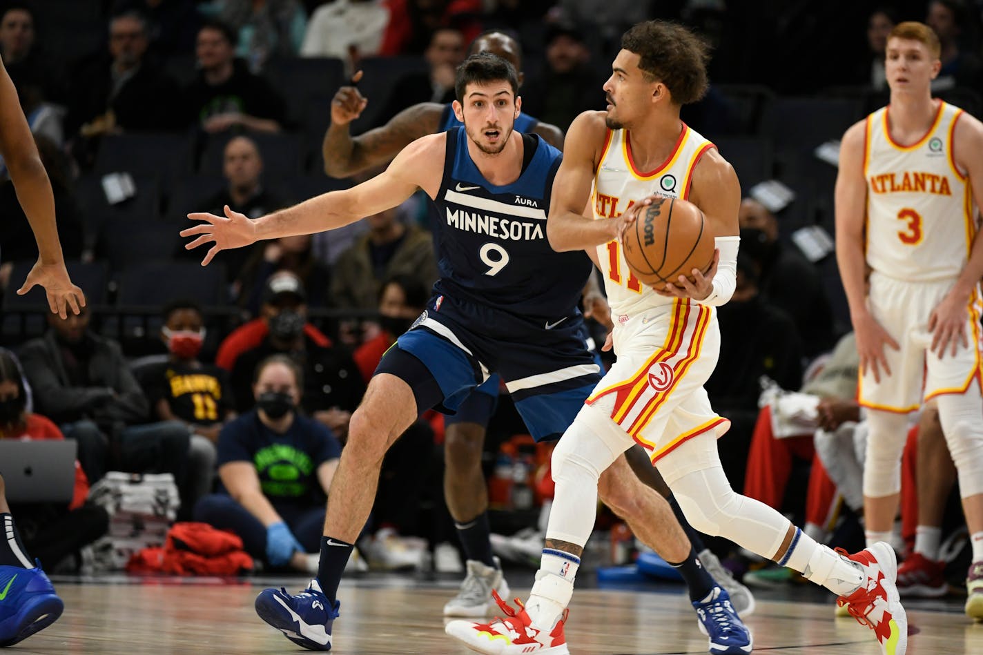 Atlanta Hawks guard Trae Young, front right, looks to pass around Minnesota Timberwolves guard Leandro Bolmaro (9) during the first half of an NBA basketball game Monday, Dec. 6, 2021, in Minneapolis. (AP Photo/Craig Lassig)